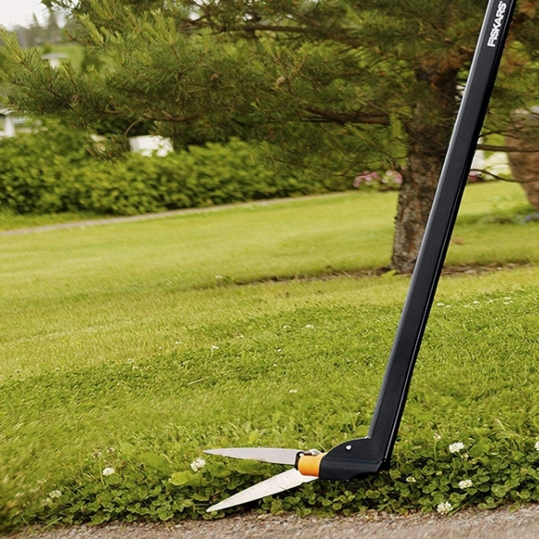 Dlhé nožnice na trávu fiskars servo gs46 02 | záhradníctvo garden team Dlhé nožnice na trávu fiskars servo gs46 precízne strihajú zelený okraj trávnika s ďatelinou pri chodníku
