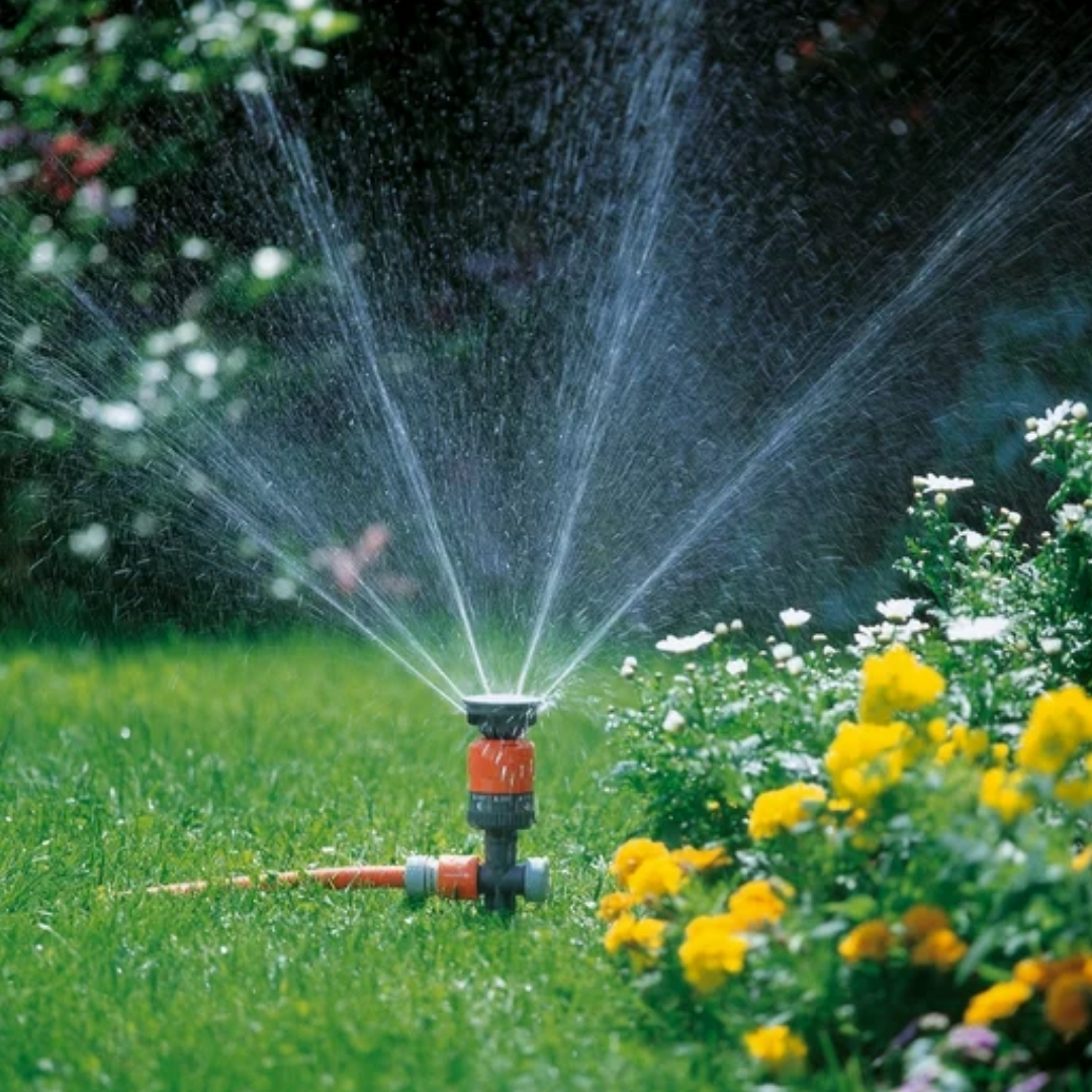 Kruhový postrekovač gardena vario 03 | záhradníctvo garden team Oranžový kruhový postrekovač gardena vario strieka jemnú vodnú hmlu na zelený trávnik a kvety